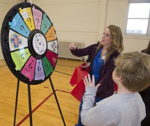 SIUE dental student Kasey Kirchner has fun with a young contestant, challenging the “Circle of Smiles,” a spinning wheel that offered oral health education and fun, at the Smile Station during the 2012 Give Kids A Smile Day.