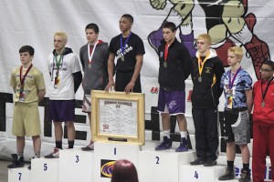 Aaron Engle (white shirt) on the podium after taking 5th place at the IKWF Wrestling State Tournament / submitted photo