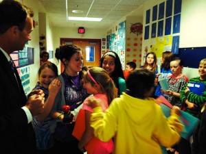 Rick Kincheloe, of Edward Jones, watches as Stephanie Ralston is embraced by a throng of adoring students after being presented with the Unit 10 Teacher of the Month award for Apri, 2014 / Photo by Laura Bauer