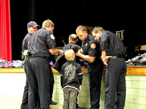 Collinsville firefighters help a Webster Elementary School student choose a coat. The firefighters are giving away 50 coats to the neediest Collinsville Unit 10 students / Photo by Roger Starkey